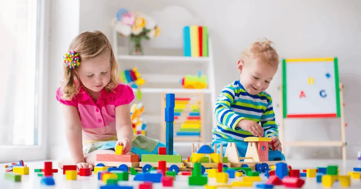 Dzieci w kolorowym pokoju zabaw budują konstrukcje z drewnianych klocków edukacyjnych